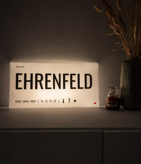 Acrylglas-Designschild „Ehrenfeld“ von DasIstColonia in einer modernen Wohnumgebung mit warmer Beleuchtung. Design Straßenschild für Köln-Liebhaber