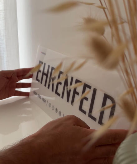 Das Acrylglas-Designschild „Ehrenfeld“ von DasIstColonia wird in den Händen gehalten und zeigt seine hochwertige Verarbeitung. Design Straßenschild für Köln-Liebhaber