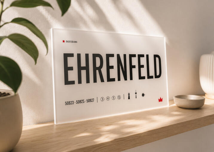 Opaline Plexiglas-Designtafel „Ehrenfeld“ von DasIstColonia auf einem hellen Regal im warmen Tageslicht. Design Straßenschild für Köln-Liebhaber